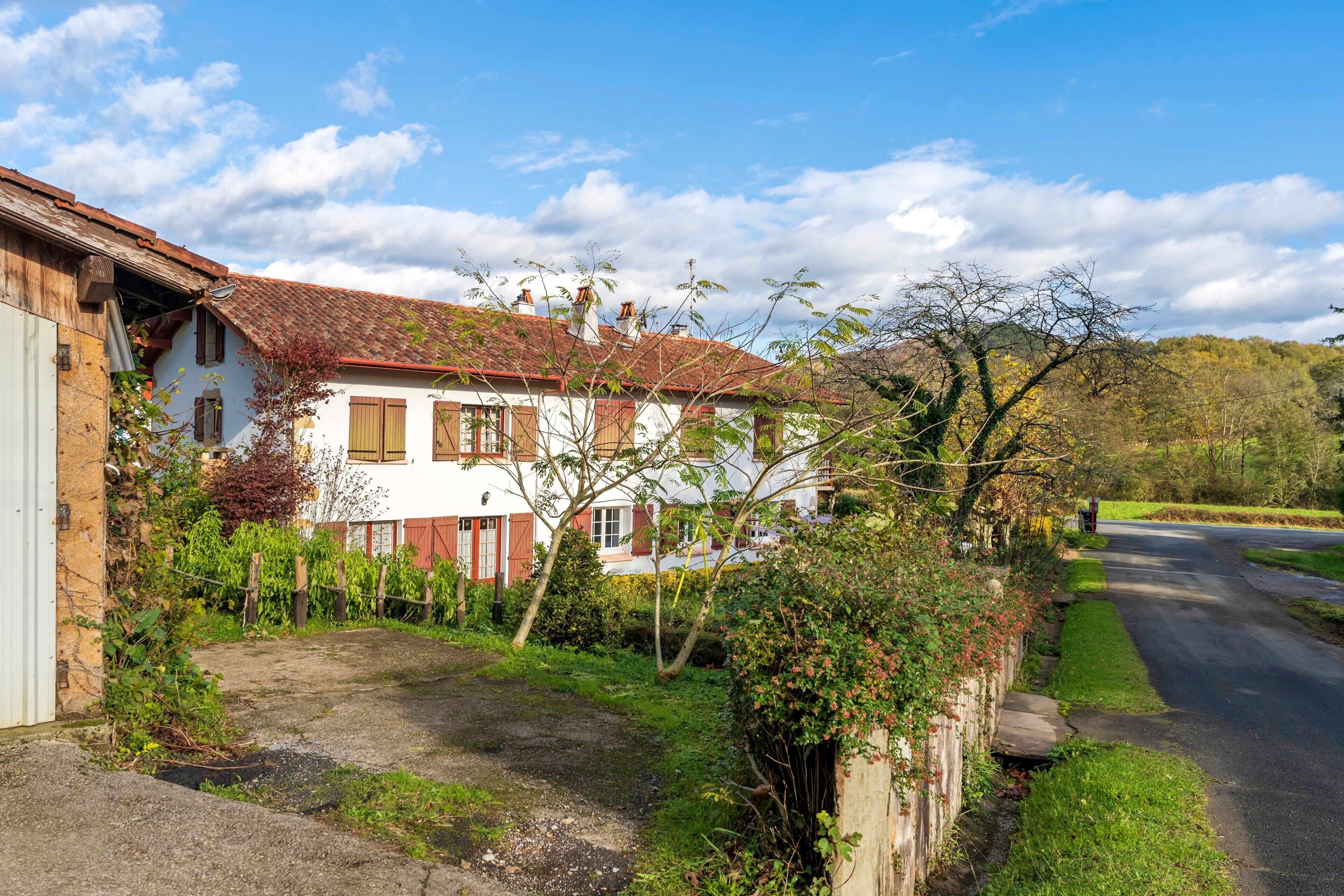 Ein zweistöckiges Haus mit rotem Ziegeldach, einem Garten und einem gepflasterten Auffahrt.