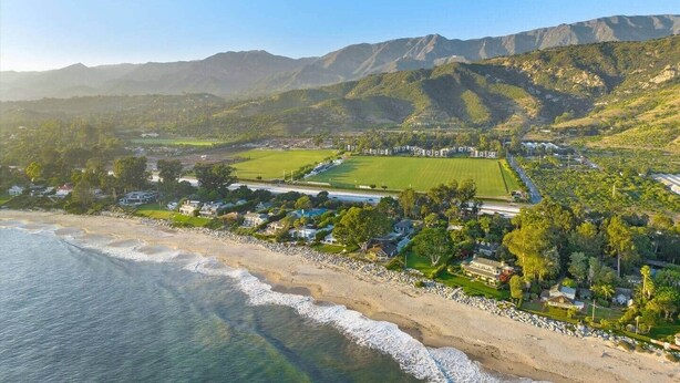 A coastal resort with beachfront properties, a large green field, and mountainous terrain in the background. - The Polo Lounge By The Sea 3BD w Large Patio (Carpinteria)
