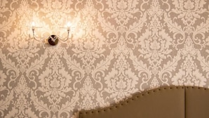 A room with a patterned wallpaper and a headboard with a tufted design. - Hotel Lo Scudiero (Turin)
