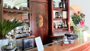 A bar area with shelves of liquor bottles, a cash register, and a potted plant. - Hotel Lo Scudiero (Turin)