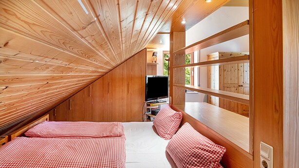 Un dormitorio con dos camas, techo de madera y televisión.