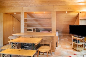Un interior de madera con una mesa de comedor, sillas, un televisor y una estantería.