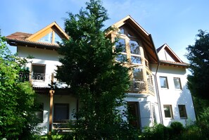 Une maison à deux étages avec un balcon, un escalier en bois et un jardin.