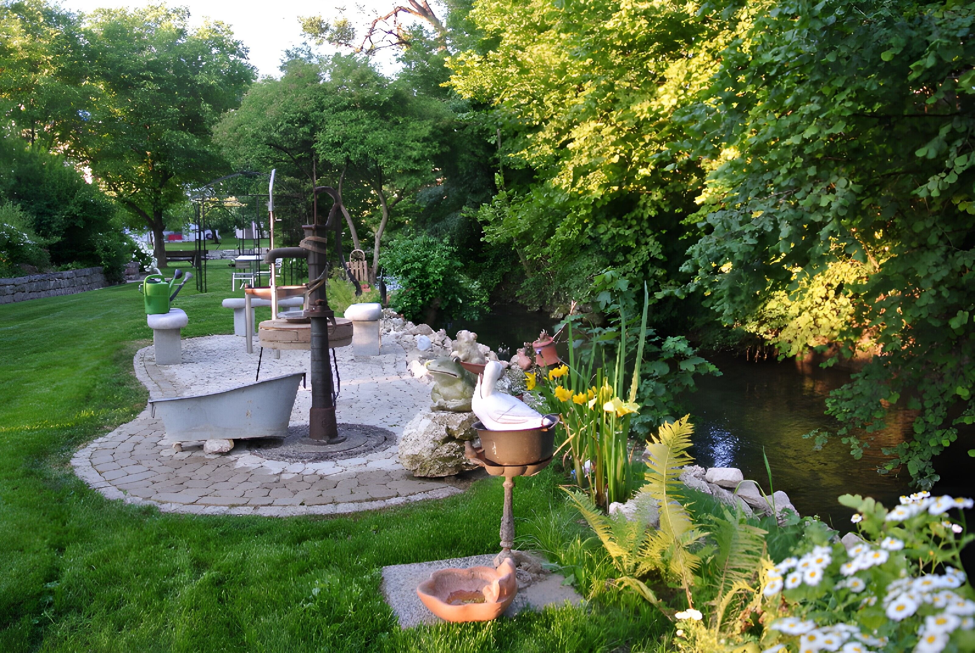 A garden with a pond, stone benches, and a bird bath.