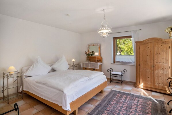 A bedroom with a bed, bedside tables, a dresser, a mirror, and a window.