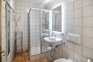 Une salle de bain avec une douche à parois de verre, un lavabo blanc et un miroir.
