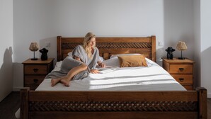 Un lit en bois avec une tête de lit, deux tables de chevet avec des lampes et une petite table de nuit avec une lampe.
