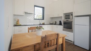 Une cuisine moderne avec des meubles blancs, une table à manger en bois et une fenêtre.