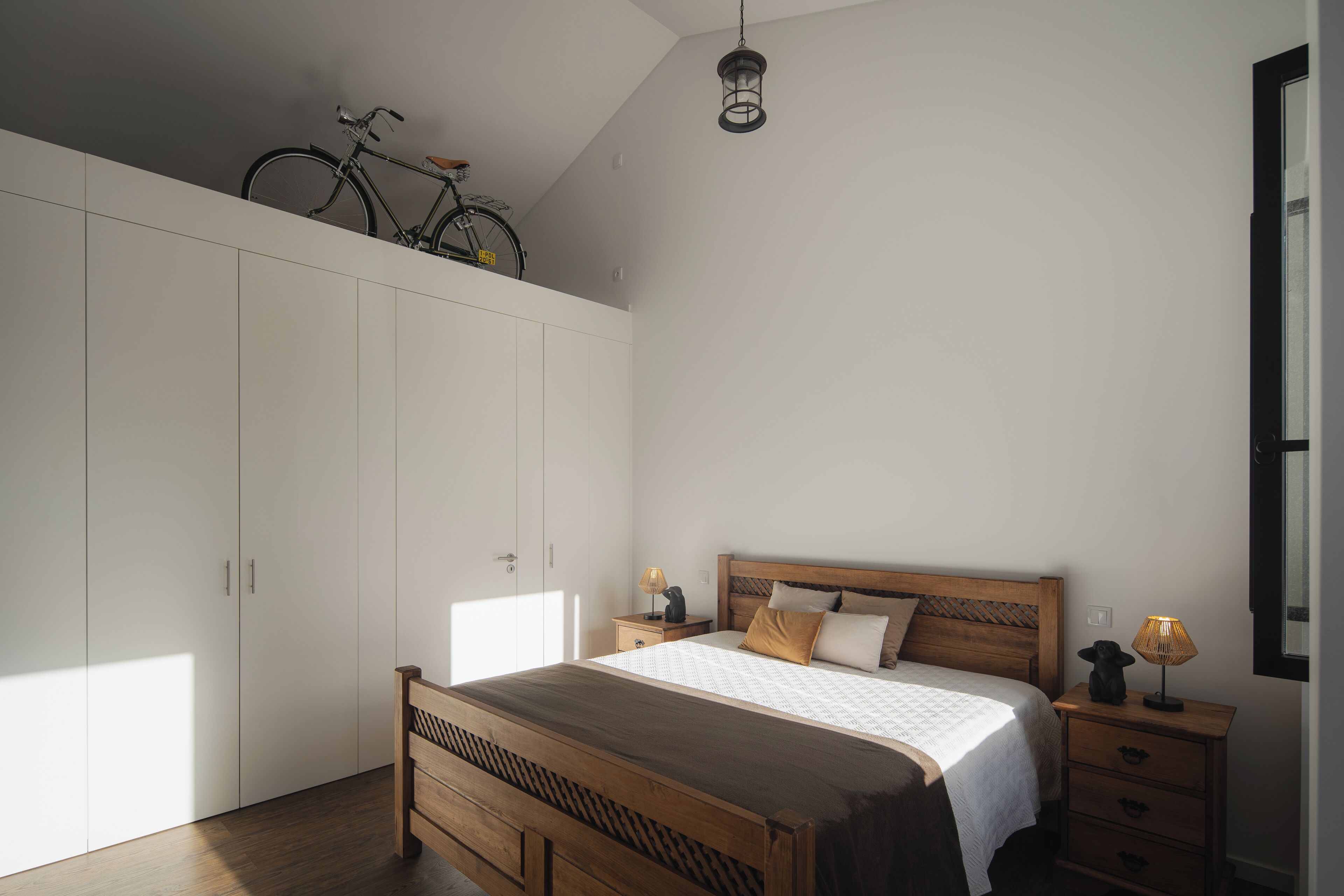 Un dormitorio con una cama de madera, una mesita de noche, un armario y una bicicleta en la esquina.