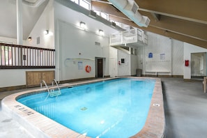Piscina interna com superfície de água translúcida, rodeada por um deck revestido de azulejos.