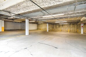 Eine Tiefgarage mit Betonpfeilern, Neonbeleuchtung und einem Schild, das Hinweise auf Parken mit Genehmigung gibt.