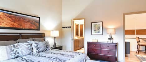 A hotel room with a bed, a dresser, a desk, and a chair.