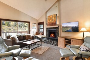 A cozy living room with a fireplace, comfortable seating, and artwork on the walls. - Tyra Summit Bluebird Condo • Ski in/out! • Pool+Hot Tubs (Breckenridge)