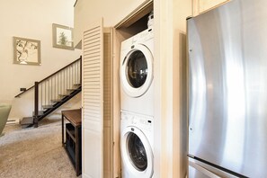 A laundry area with a washing machine and dryer, a staircase, and a refrigerator. - Tyra Summit Bluebird Condo • Ski in/out! • Pool+Hot Tubs (Breckenridge)