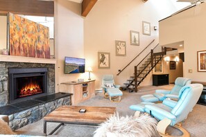 Ein Wohnzimmer mit Kamin, Treppe und einem großen Gemälde an der Wand.