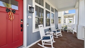 A red door with a bow, white rocking chairs, and a porch with a railing. - Harbor Shores 3BR in St. Joseph | Community Pool, Sleeps 8, Near Silver Beach (St Joseph)