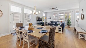 A spacious living area with a dining table set for four, surrounded by wicker chairs. A ceiling fan and a chandelier are visible. - Harbor Shores 3BR in St. Joseph | Community Pool, Sleeps 8, Near Silver Beach (St Joseph)