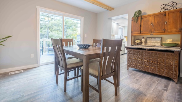 A dining area with a wooden table and chairs, a ceiling fan, and a kitchen with wooden cabinets and a countertop. - 8 mins to Lake Monroe • Grill • Firepit • By IU (bloomington)