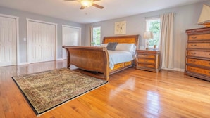 A bedroom with a wooden bed, a nightstand, a dresser, and a ceiling fan. - 8 mins to Lake Monroe • Grill • Firepit • By IU (bloomington)