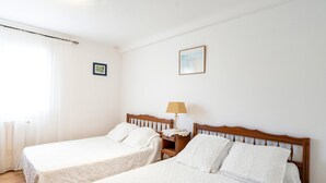 Two single beds with wooden headboards, a nightstand with a lamp, and a framed picture on the wall.