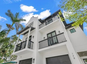 Un edificio residencial de varios pisos con balcones, puertas de garaje y cielo despejado.
