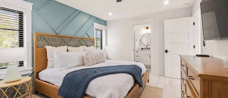 Een slaapkamer met een bed, een plafondventilator, een dressoir en een televisie.