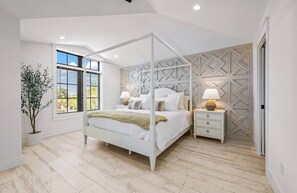 A bedroom with a four-poster bed, a nightstand, a lamp, a potted plant, and a window with blinds. - New 8/8 bathroom beach house! Heated pool and spa! (Sarasota)