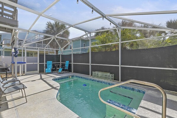 Une piscine intérieure dotée d’un toit en verre, de chaises disposées au bord de la piscine et d’un fauteuil de détente bleu.