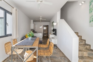 A modern interior with a dining area, kitchen, and staircase.