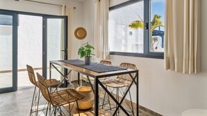 A dining area with a table, chairs, a potted plant, and a view through a window. - Casa Bidasoa 35: Sea Views, Shared Pool & Wi-Fi in Playa Blanca (Playa Blanca)