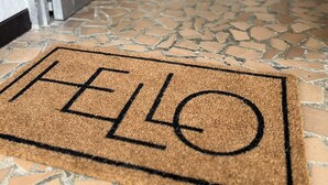 A doormat with "HELLO" written on it, leading to a room with a tiled floor and a window in the background.
