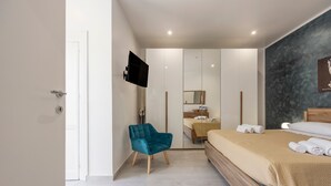 A modern bedroom with a bed, a chair, a TV, and a mirror. - La terrazza di porticello (Porticello)
