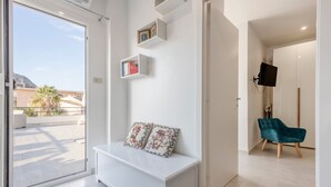 A modern living room with a white bench, a teal chair, and a mounted TV. - La terrazza di porticello (Porticello)