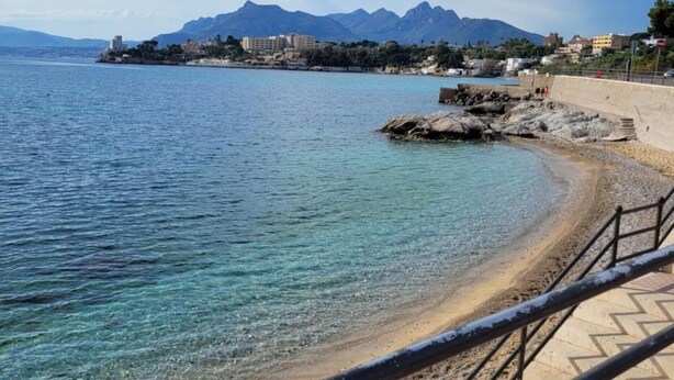 A coastal beach with clear water, a stone pathway, and distant mountains. - La terrazza di porticello (Porticello)