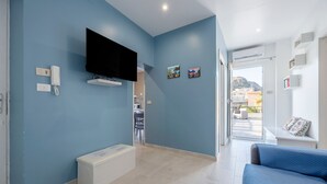 A modern room with a flat-screen TV, a bench, and a bed. - La terrazza di porticello (Porticello)