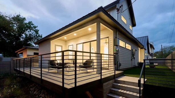 A modern house with a covered porch, a staircase, and a fenced deck area. - Sleeps 20, 5br Pool table, Chef's Kitchen, Pool (Austin)