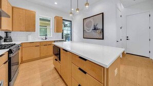 A modern kitchen with wooden cabinets, a white countertop, and pendant lighting. - Sleeps 20, 5br Pool table, Chef's Kitchen, Pool (Austin)