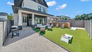 A modern two-story house with a patio area featuring outdoor furniture and artificial grass. - Sleeps 44, Luxury Compound, 2 Pools, 2 Kitchens (Austin)
