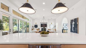 A modern kitchen with a marble countertop, stainless steel appliances, and pendant lighting. - 7BR Estate - Pool on Golf Course - 4mi to Downtown (Austin)