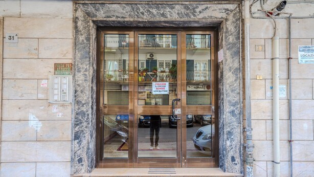 Μια είσοδος κτιρίου με μια μαρμάρινη πρόσοψη, μια πινακίδα που υποδεικνύει μια περιοχή όπου απαγορεύεται το κάπνισμα και μια πόρτα που είναι εύκολα ορατή.