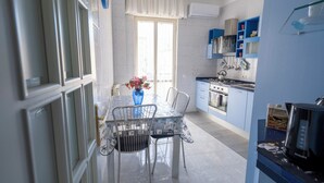 Μια σύγχρονη κουζίνα με τραπεζαρία, η οποία περιλαμβάνει ένα τραπέζι με καρέκλες, ένα βάζο με λουλούδια και μια καφετιέρα.