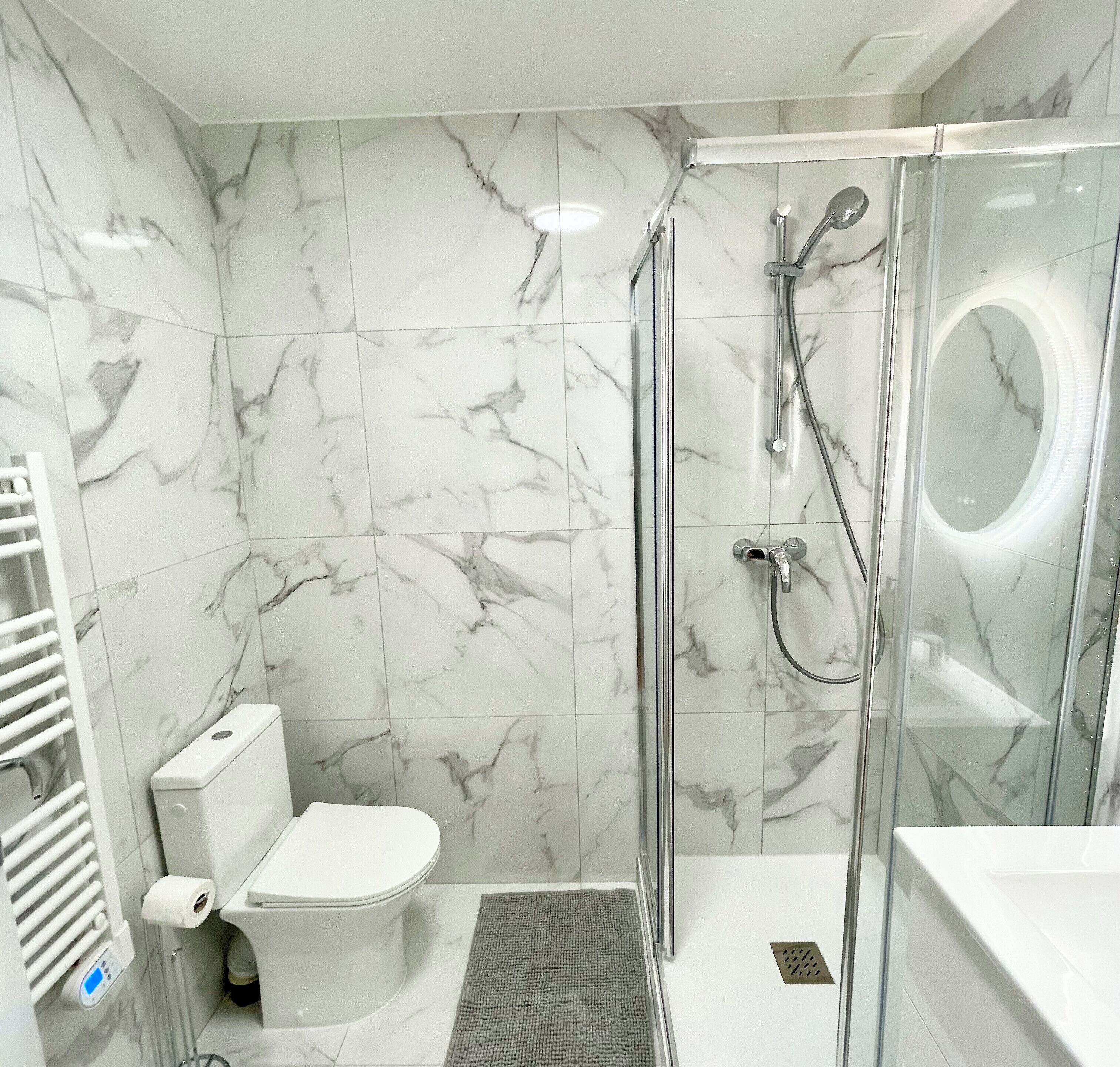 Een moderne badkamer met een douchecabine van glas, een toilet en een wastafel.