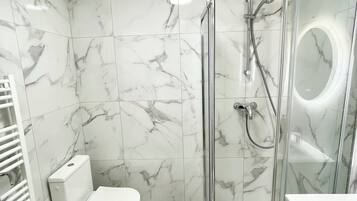 Een moderne badkamer met een douchecabine van glas, een toilet en een wastafel.