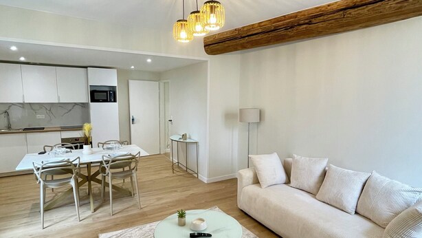 A modern living room with a sofa, a coffee table, and a dining area with a table and chairs. - Casa Luna – 1 Bedroom, 4 Guests, City Center, Fully Equipped (Metz)