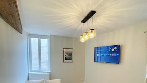 A bedroom with a bed, a small round table, a TV mounted on the wall, and a window. - Casa Luna – 1 Bedroom, 4 Guests, City Center, Fully Equipped (Metz)