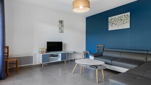A modern living room with a flat-screen TV, a sofa, a coffee table, and a blue accent wall. - Villa 'Gite Les Bouches Rouges 6 Personnes' with Mountain View, Wi-Fi and Air Conditioning (Vesseaux)
