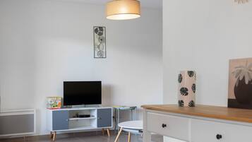 Un salon moderne avec un téléviseur à écran plat, un meuble, une table et une chaise.