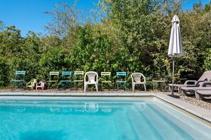 A swimming pool with lounge chairs and umbrellas, surrounded by dense foliage. - Villa 'Gite Les Bouches Rouges 6 Personnes' with Mountain View, Wi-Fi and Air Conditioning (Vesseaux)