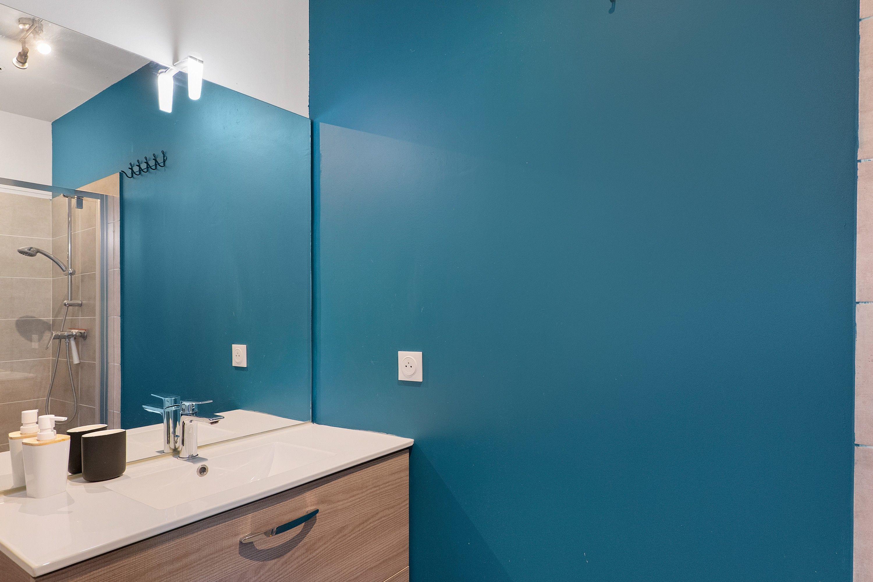 Un baño con un lavamanos blanco, un espejo y una ducha.