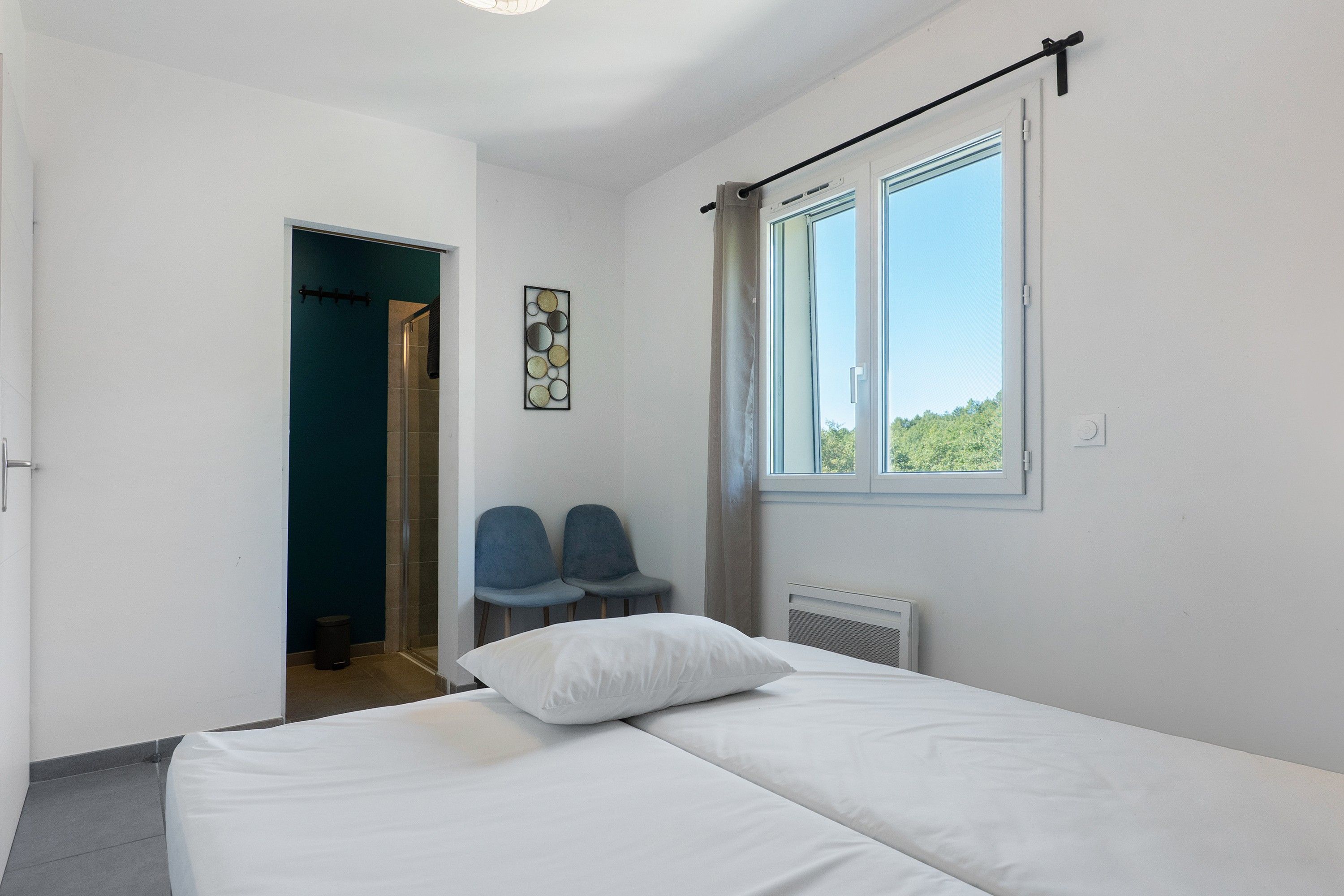 Ein Schlafzimmer mit einem Bett, zwei Stühlen, einem Fenster und einer Tür.